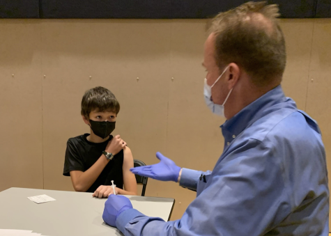 Andrew Mac asks Thomas Rouillard 28, Which superpower would you rather have, invisibility or the ability to fly? as he gave the sixth grader his COVID-19 vaccine.