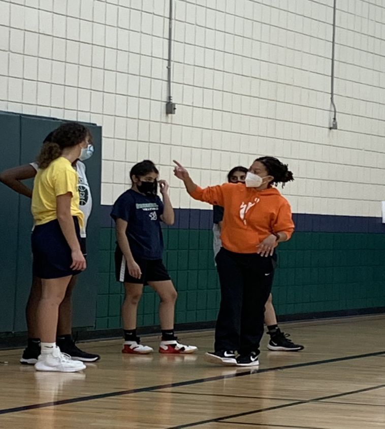 PUT+ME+IN%2C+COACH+Janelle+Sterling+%28in+orange%29+gives+instructions+during+a+huddle+at+basketball+practice.+Greenhills+is+Sterlings+first+varsity+head+coaching+position.+She+has+coached+at+almost+all+levels+including+recreational+basketball%2C+middle+school%2C+junior+varsity%2C+and+has+been+a+varsity+assistant+coach.